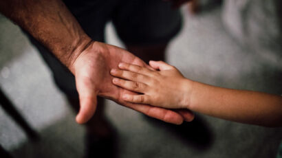 An adult holding a child by the hand